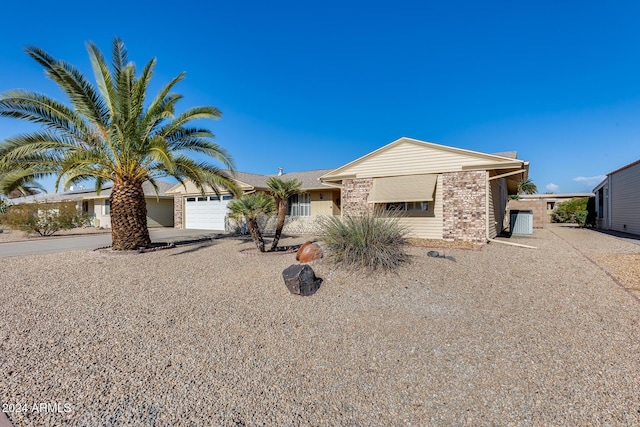 single story home with central AC unit and a garage