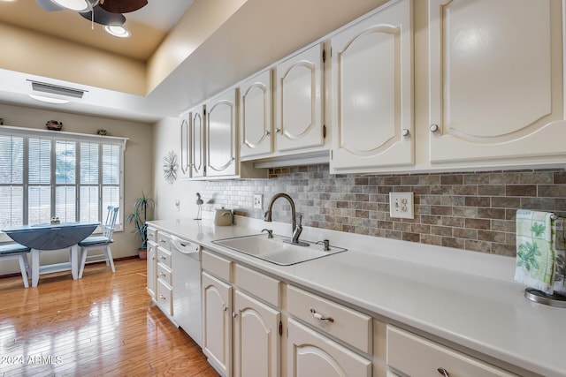 kitchen featuring backsplash, white dishwasher, sink, white cabinets, and light hardwood / wood-style floors