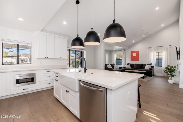 kitchen featuring light countertops, vaulted ceiling, a sink, light wood-type flooring, and dishwasher