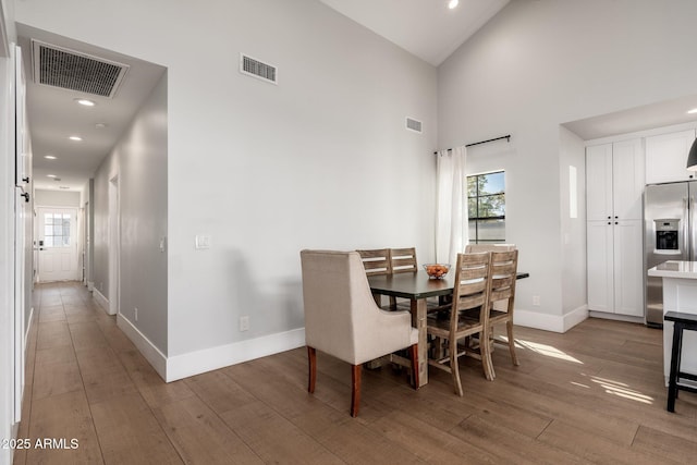 dining space with light wood-type flooring, visible vents, and baseboards