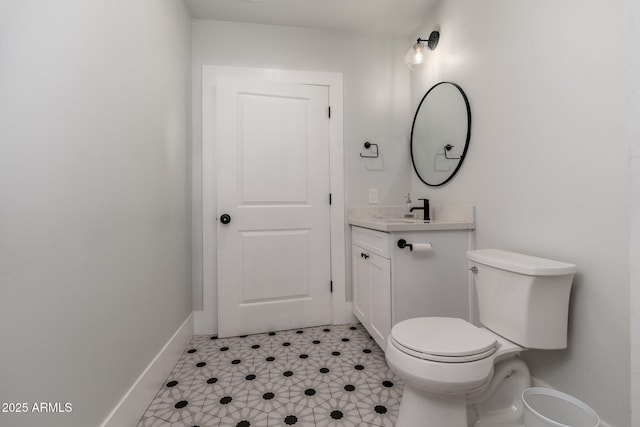 half bathroom with toilet, baseboards, and vanity