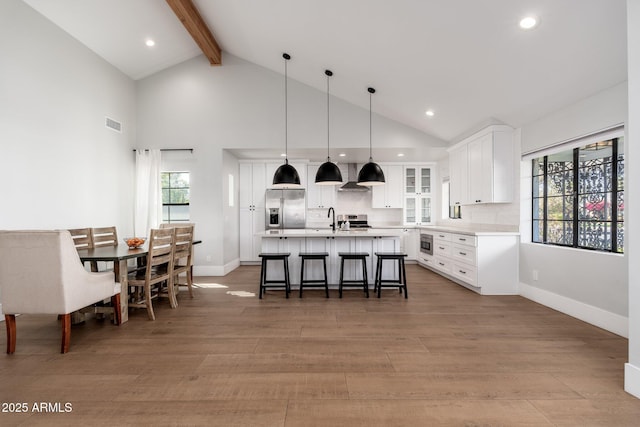 kitchen with a breakfast bar, stainless steel appliances, light countertops, white cabinetry, and light wood-type flooring