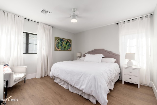 bedroom featuring light wood-type flooring, visible vents, ceiling fan, and baseboards