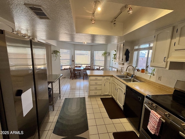 kitchen with sink, light tile patterned floors, kitchen peninsula, stainless steel appliances, and white cabinets