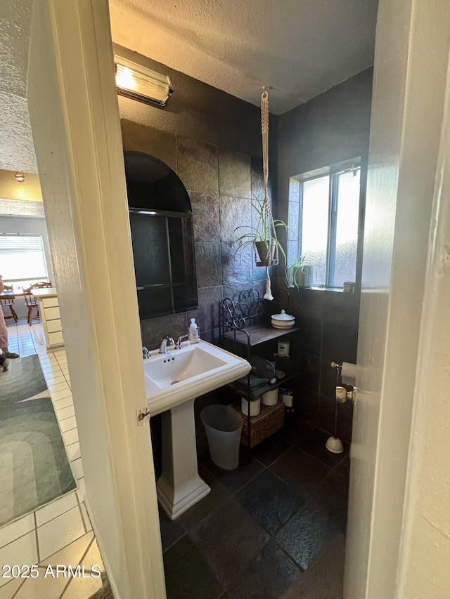 bathroom featuring backsplash, tile walls, and a textured ceiling