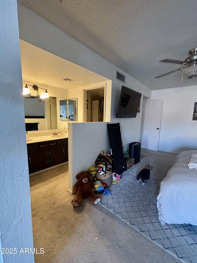 carpeted bedroom with sink, ensuite bath, and a textured ceiling