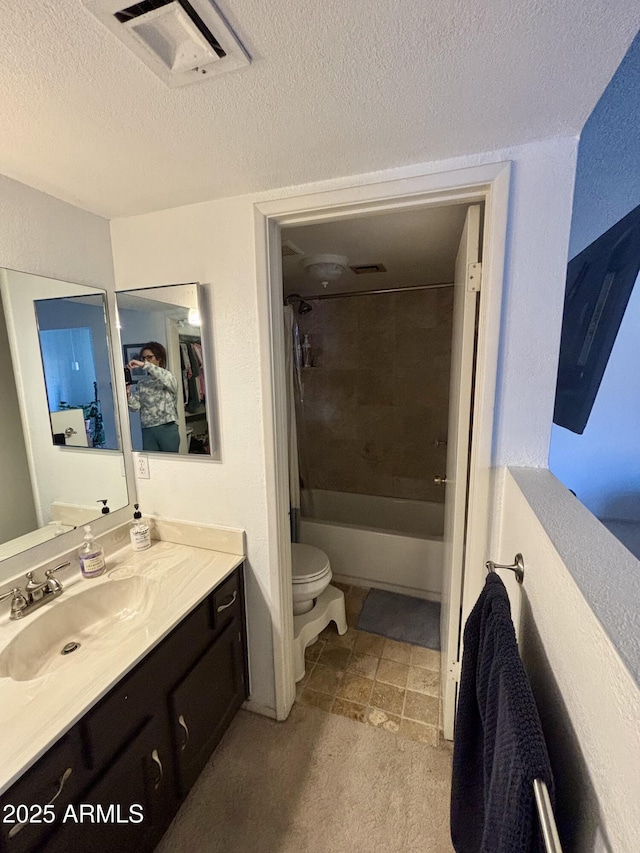 full bathroom with tiled shower / bath, vanity, toilet, and a textured ceiling