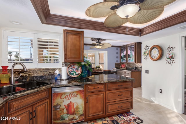 kitchen featuring sink, crown molding, dark stone countertops, stainless steel dishwasher, and a raised ceiling