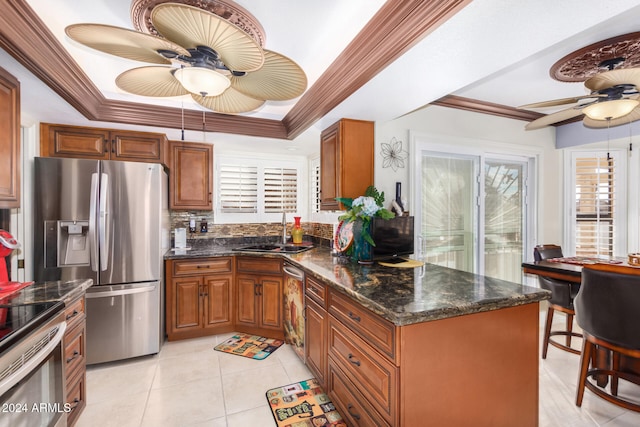 kitchen with ornamental molding, stainless steel appliances, a raised ceiling, and sink