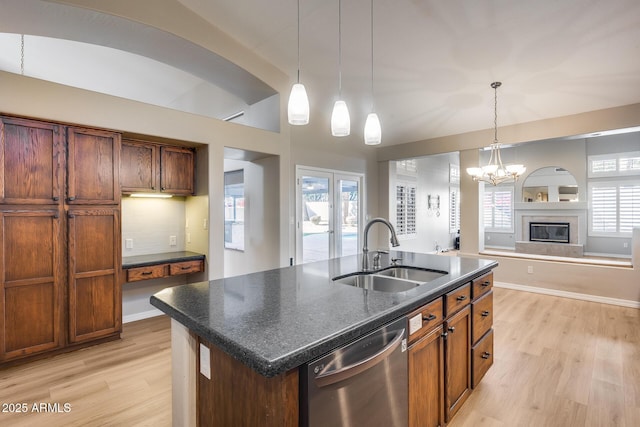 kitchen featuring dishwasher, an island with sink, light hardwood / wood-style floors, and sink