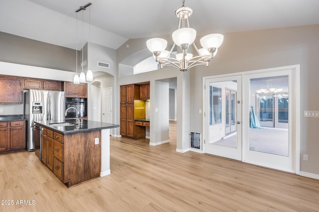 kitchen featuring a chandelier, pendant lighting, black oven, and an island with sink