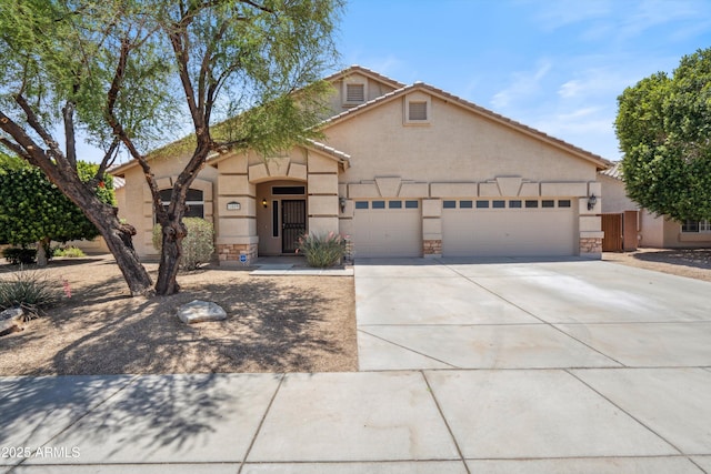 1029 E Ian Dr, Phoenix, AZ 85042 - view of front of house featuring an attached garage, concrete driveway, stone siding, and stucco siding