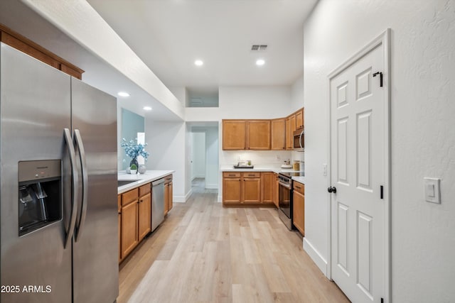 1029 E Ian Dr, Phoenix, AZ 85042 - kitchen with stainless steel appliances, light wood finished floors, brown cabinets, light countertops, and recessed lighting
