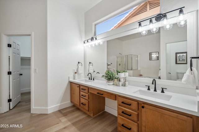 1029 E Ian Dr, Phoenix, AZ 85042 - full bathroom featuring double vanity, wood finished floors, a stall shower, toilet, and a spacious closet