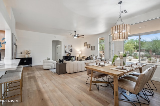 1029 E Ian Dr, Phoenix, AZ 85042 - dining room featuring arched walkways, light wood-style floors, a ceiling fan, a chandelier, and baseboards