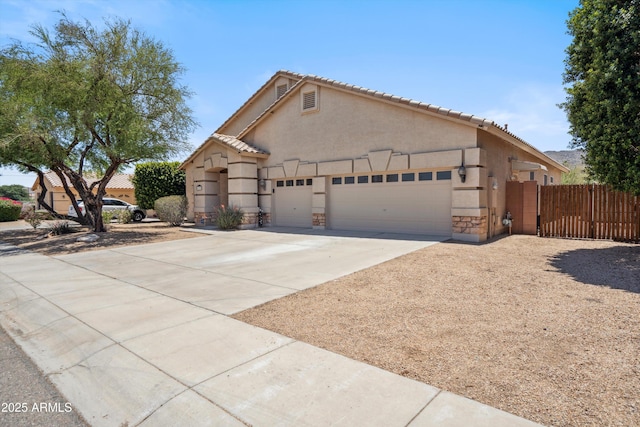 1029 E Ian Dr, Phoenix, AZ 85042 - view of front facade featuring an attached garage, concrete driveway, stucco siding, stone siding, and a tiled roof