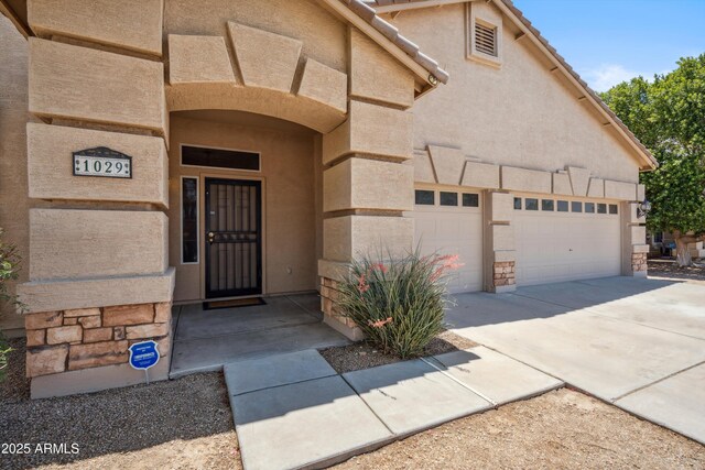 1029 E Ian Dr, Phoenix, AZ 85042 - entrance to property with concrete driveway, an attached garage, stucco siding, and stone siding