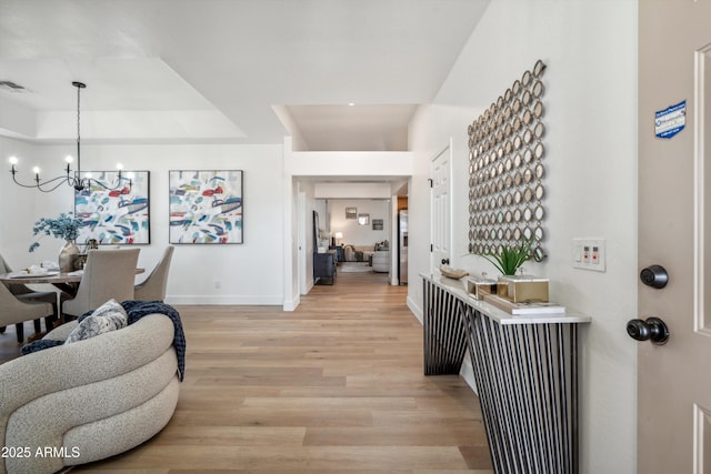 1029 E Ian Dr, Phoenix, AZ 85042 - foyer entrance featuring a chandelier, baseboards, light wood-type flooring, and a raised ceiling