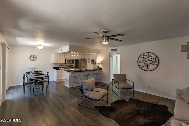 living room with ceiling fan and dark hardwood / wood-style flooring