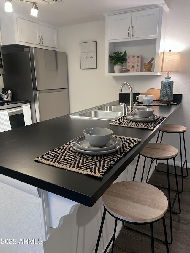 kitchen featuring white cabinets, stainless steel appliances, a kitchen bar, and dark hardwood / wood-style floors