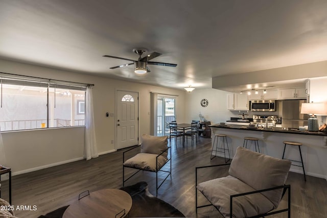 living room featuring ceiling fan, sink, and dark hardwood / wood-style flooring