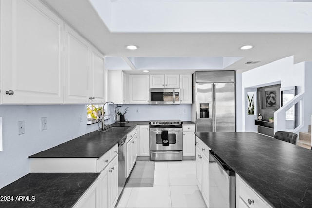 kitchen with appliances with stainless steel finishes, light tile patterned floors, plenty of natural light, sink, and white cabinets