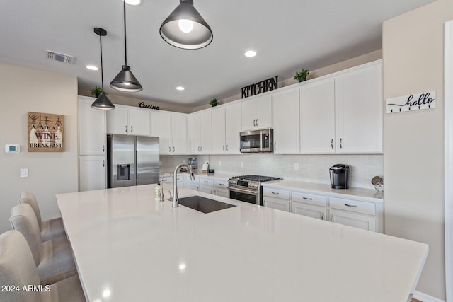 kitchen featuring a breakfast bar, a large island with sink, sink, appliances with stainless steel finishes, and tasteful backsplash