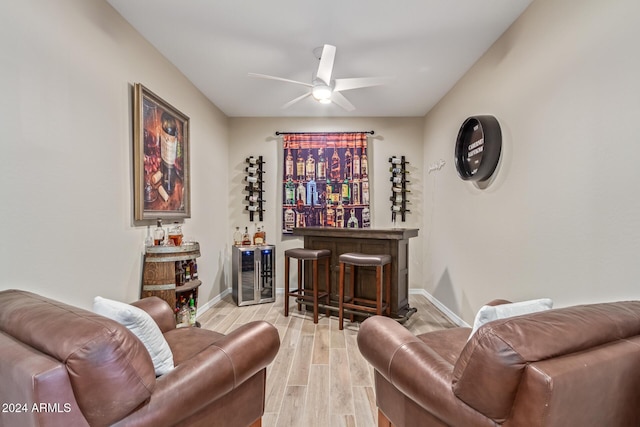 interior space featuring ceiling fan, beverage cooler, light wood-type flooring, and bar