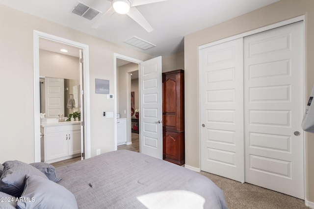 carpeted bedroom featuring ceiling fan, sink, ensuite bathroom, and a closet