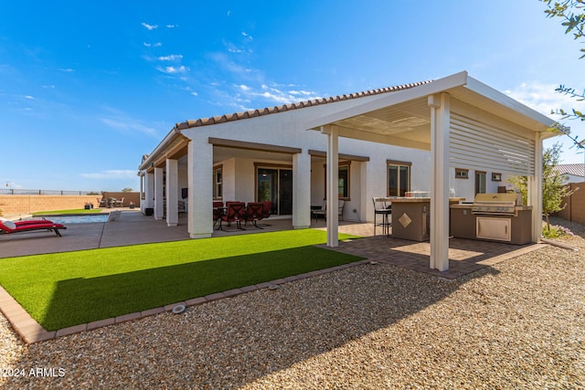 rear view of property with a lawn, a patio area, and exterior kitchen