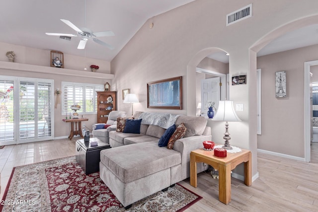 living area featuring light wood finished floors, baseboards, visible vents, and arched walkways