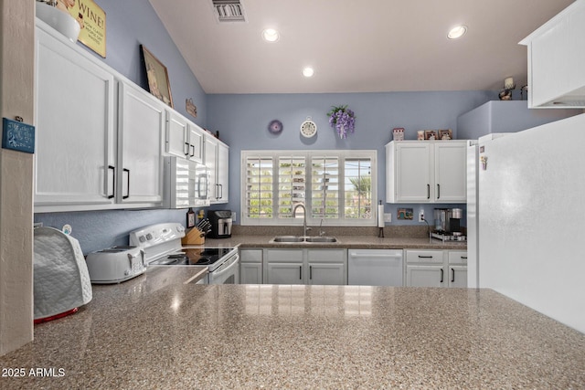 kitchen with white appliances, visible vents, white cabinets, a sink, and recessed lighting