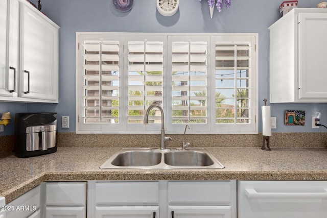 kitchen featuring dishwashing machine, white cabinets, a sink, and light countertops