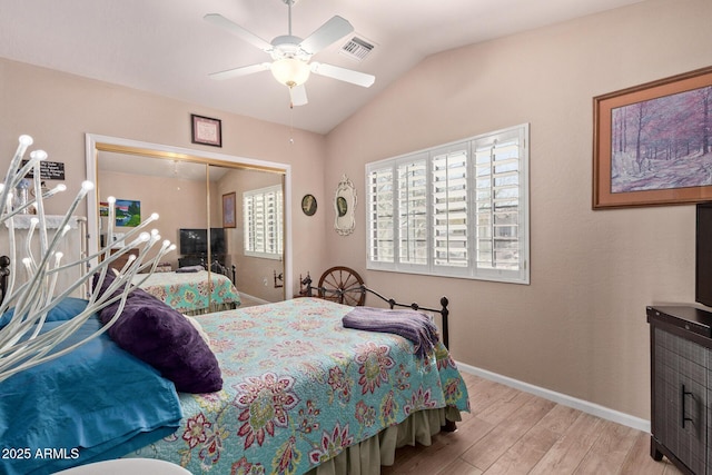 bedroom with baseboards, visible vents, lofted ceiling, wood finished floors, and a closet