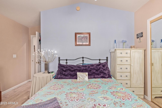 bedroom featuring light wood-style floors, baseboards, and vaulted ceiling