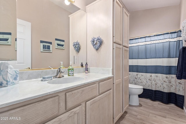 bathroom featuring toilet, curtained shower, wood finished floors, and vanity