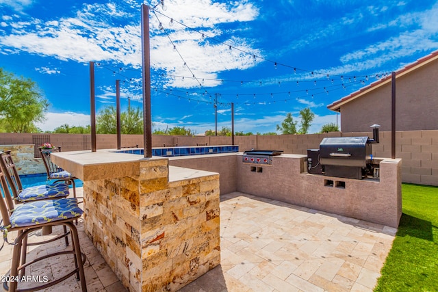 view of patio / terrace with exterior bar, an outdoor kitchen, and area for grilling