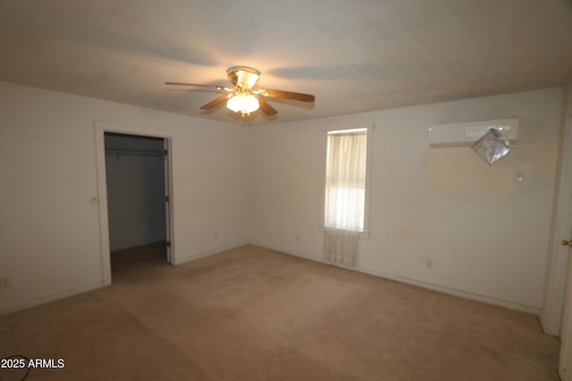 unfurnished bedroom with baseboards, a wall mounted air conditioner, light colored carpet, a spacious closet, and a ceiling fan