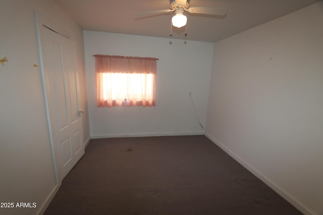 carpeted spare room featuring a ceiling fan and baseboards