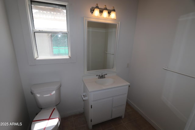 bathroom with vanity, baseboards, toilet, and a wealth of natural light