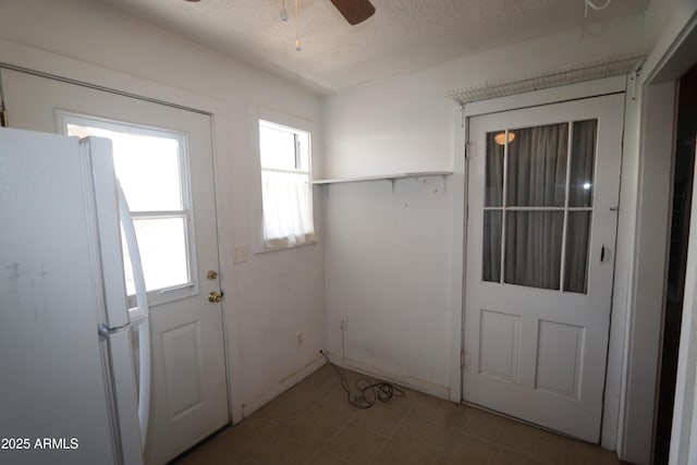 doorway to outside featuring a healthy amount of sunlight, tile patterned floors, a ceiling fan, and a textured ceiling
