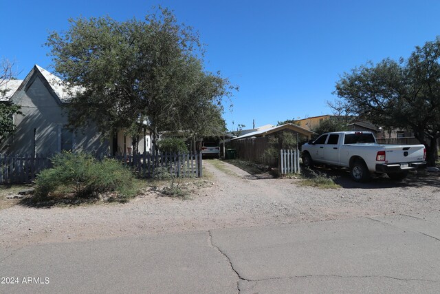 view of property hidden behind natural elements with fence and dirt driveway