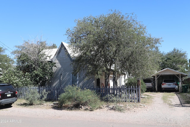 view of home's exterior with dirt driveway, a detached carport, and fence