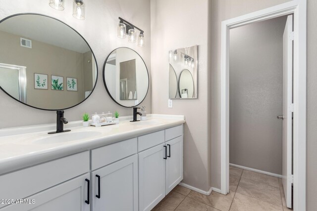 bathroom with double vanity, tile patterned flooring, visible vents, and a sink