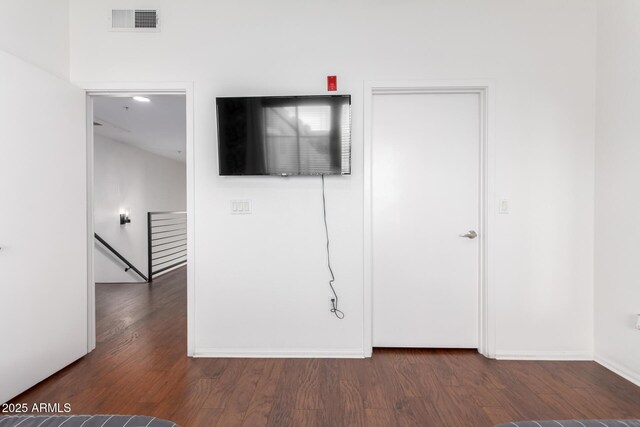 unfurnished bedroom with dark wood-style floors, visible vents, and baseboards