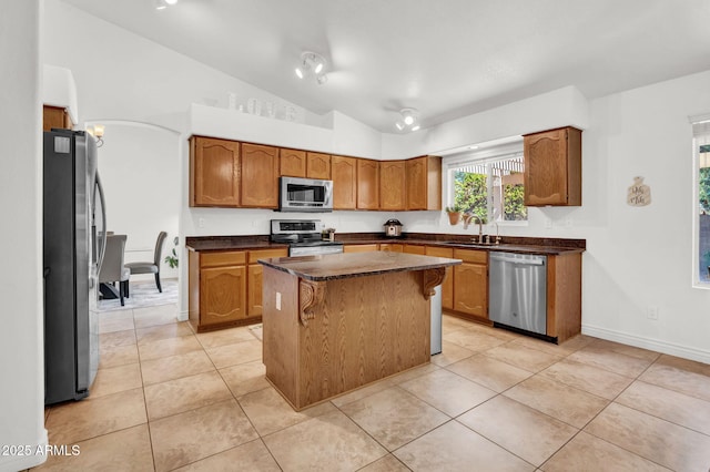 1831 W Armstrong Way, Chandler, AZ 85286 - kitchen with appliances with stainless steel finishes, brown cabinets, dark countertops, a kitchen island, and vaulted ceiling