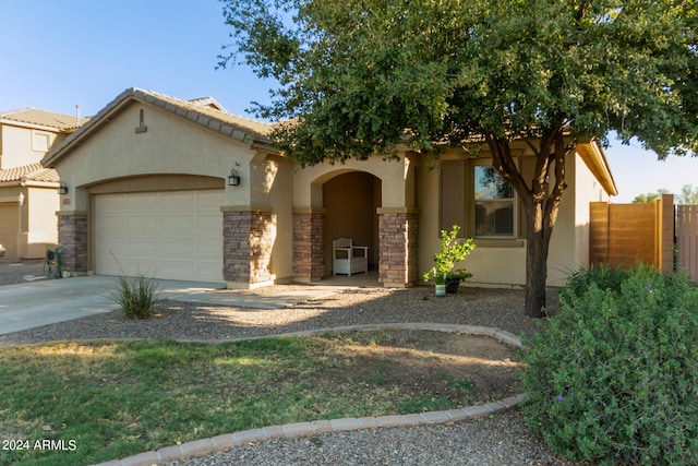 view of front of home featuring stucco siding, an attached garage, concrete driveway, stone siding, and fence