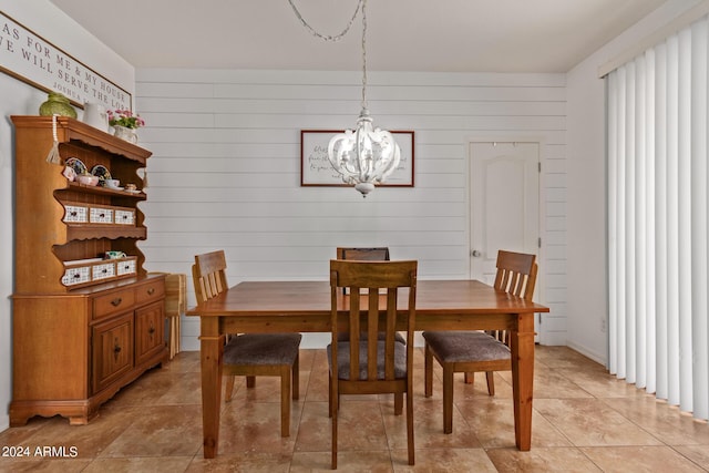 dining area with a chandelier and wooden walls