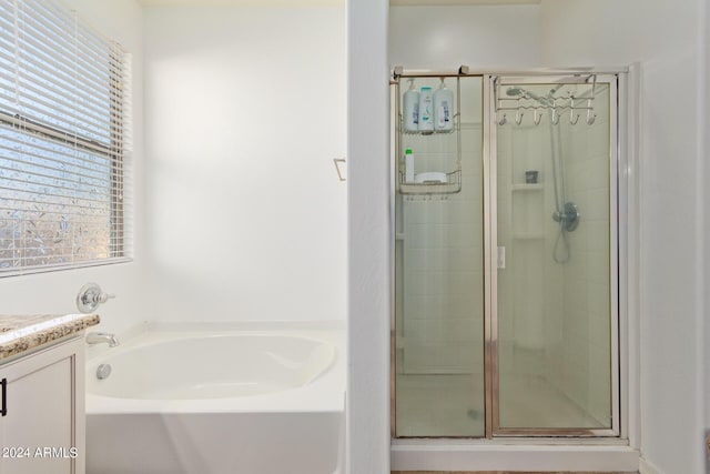 full bathroom featuring a stall shower, a bath, and vanity