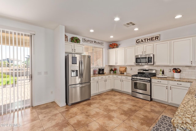 kitchen featuring appliances with stainless steel finishes, decorative backsplash, white cabinetry, light stone counters, and recessed lighting